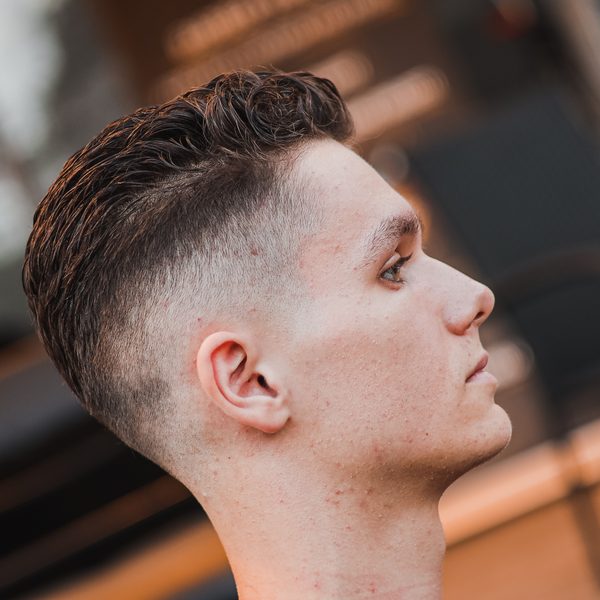 Detail sestřihu z profilu s vyholenými boky a delší kudrnatou ofinou