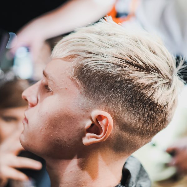 Detail blond účesu s vyholenými boky a nahoru vyčesanou ofinou